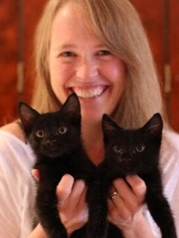 Woman holding up two black kittens