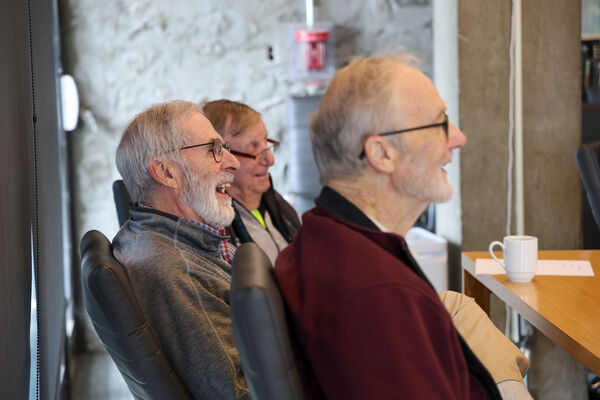 Three men seated at a meeting.