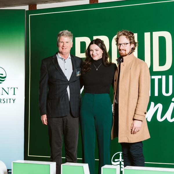 3 people smiling on stage at an awards reception