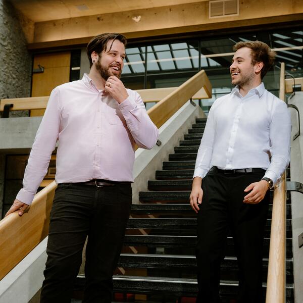 2 men in business attire walking down stairs talking